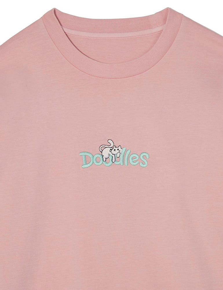 Dusty pink Doodles Mello Long Sleeve T-Shirt featuring an embroidered design of Mello lounging atop the Doodles logo, made from 100% cotton for a soft and comfortable fit. Logo close-up view.